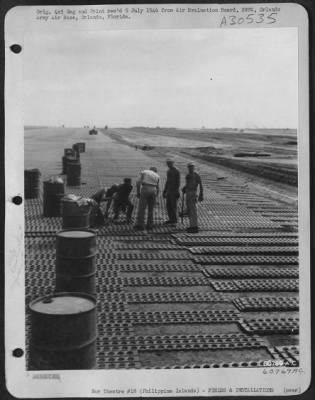 Consolidated > Engineers of the 1913th Aviation Engineer Battalion laying steel matting on airstrip at Clark Field, Luzon, Philippine Islands. 13 June 1945.