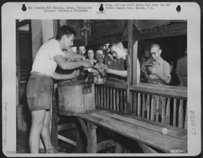 Consolidated > In the dreary basement of the Santo Tomas Prison, G.I.'s dole out food to the hungary internees. February 1945. Manila, Luzon, Philippine Islands.