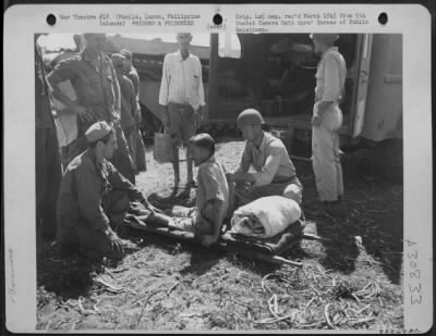 Consolidated > Internee wounded in the taking of a prison camp, at Manila, Luzon, Philippine Islands, is placed on a stretcher prior to evacuation.