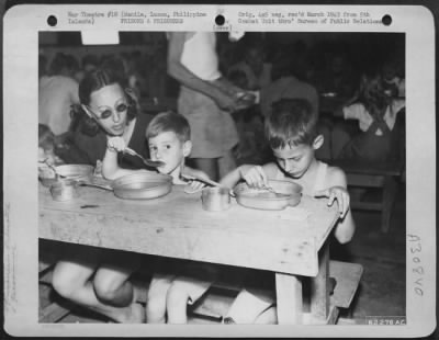 Consolidated > Mrs. Bertha Palmer, Manchester, England, and her two sons, John and Ronald, eat their first meal after being liberated from the Los Banos Prison, Manila, Luzon, Philippine Islands.