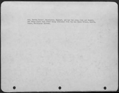 Consolidated > Mrs. Bertha Palmer, Manchester, England, and her two sons, John and Ronald, eat their first meal after being liberated from the Los Banos Prison, Manila, Luzon, Philippine Islands.