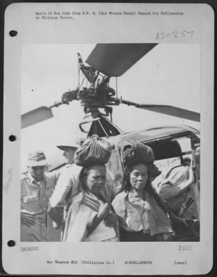 Thumbnail for Consolidated > The first AAF helicopter to operate in the Philippines perplexes two native women in a Leyte town. (Those are bundles of GI laundry on their heads).