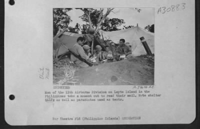 Consolidated > Men of the 11th Airborne Division on Leyte Island in the Philippines take a moment out to read their mail. Note shelter balfs as well as parachutes used as tents.