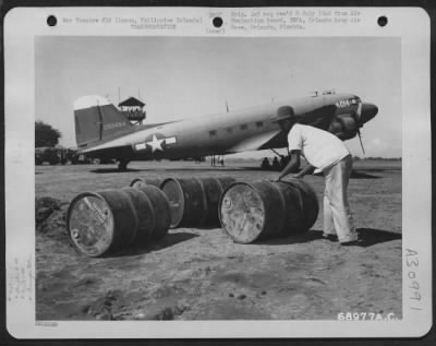 Consolidated > A native laborer moves fuel drums which have been unloaded from a Douglas C-47 of the 318th Troop Carrier Commandos at Laoag Air Strip on Luzon, Philippine Islands. 20 May 1945.