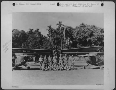 Consolidated > Vultee L-5 Pilots Of The 1St Air Commando Group Standing In Front Of An L-1 Plane Which Is Used For Evacuation Of Wounded. L-5 Planes Are Seen On Either Side.