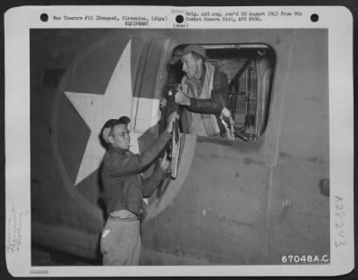 Thumbnail for Consolidated > At an air base near Bengasi, Cirenaica, Libya, S/Sgt. Joseph E. Tamuleirz of Millis, Mass., hands a "flak suit" through the waist windown of a Liberator to T/Sgt. William G. Jordan of Columbia, S.C. The "flak suit" is designed to protect American