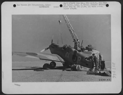 Thumbnail for Consolidated > A fighter with its tail off in for repair at a forward maintenance depot at Tripolitania. A mobile crane mounted on a lorry is being used to support it while it is being repaired.