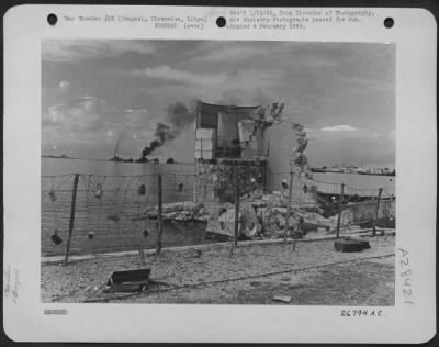 Thumbnail for Consolidated > A wrecked building on the waterfront at Bengasi, Cirenaica, Libya, target of the "Mail Run" bombers for months. On the horizon is an oil tanker which has been burning for more than three weeks.