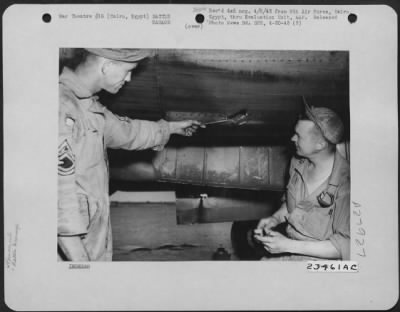 Consolidated > Cairo, Egypt-"It went right in there, boy!" T/Sgt. Loyd A. Rogers of Patterson, Louisiana, and Sgt. Knute H. Leirmore, Mt. Sterling, Wisc., look at a hole in the engine caused by Ack-Ack fire after returning from a bombing mission over the Mareth
