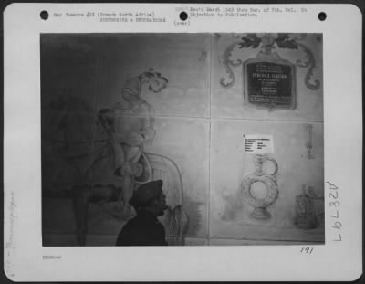 Thumbnail for Consolidated > An American Flyer who toured the headquarters of the French Foreign Legion, admires the decoration on the wall of the enlisted men's recreation hall. The murals were painted by artists from the ranks.