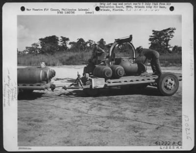Consolidated > By using a special hoist and truck, AAF personnel load 1000 pound bombs onto a trailer. Bomb Storage and supply dump, Clark Field, Luzon, Philippine Islands. 1 June 1945.