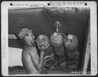 Consolidated > Member of the Armament Crew loads 260 pound fragmentation bombs onto the wing tank rack of a North American P-51 "Mustang." Each rack holds three bombs. Clark Field, Manila, Luzon, Philippine Islands. 1 June 1945.
