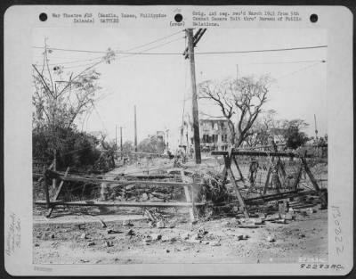 Thumbnail for Consolidated > This photo shows the type of road block used by the Japanese in Manila, Luzon, Philippine Islands. They were erected of timbers and barbed wire and were meant to stop traffic momentarily as well as force the drivers of vehicles to step out of the car