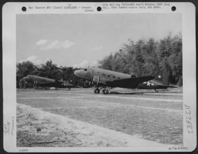 Thumbnail for Consolidated > Douglas C-47 troop carrier planes of the 1st Air Commando Force, used as glider tow planes, were displaced among the trees bordering each side of the grass airstrip at Hailakandi, India. The white ball and question mark on the tail structure was the