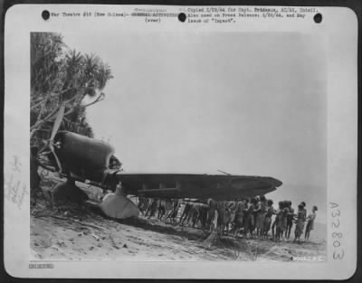 Consolidated > Japanese Aichi 99 "Val" is dragged up on a New Guinea Beach by Natives, "Bongs" for Technical Intelligence Officers.