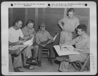 Consolidated > John McCormack of the American Red Cross explains the technique of making crayon drawings to Major Emmett S. Davis of Compton, California, commanding officer of the 35th Fighter Squadron, 8th Fighter Group at Port Moresby, New Guinea. Looking