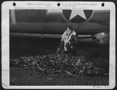 Gunner > S/Sgt. Robert L. Taylor kneeling next to a pile of empty .50 cal. Machine gun shells.