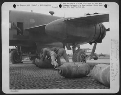 Thumbnail for Consolidated > Armament workers roll a thousand pounder under the bomb bay of a B-25 Mitchell bomber for loading. The Mitchells in the 12th AAF have been striking hard at German roads and railroads in Italy. One of these big bombs on a road is sufficient to block