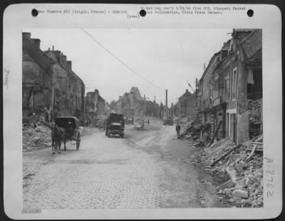 Thumbnail for Isigny > Street scene in the liberated town of Isigny, France, shows civilians along with soldiers of the Allies. The people of this little village have alreadt begun to clean up the wreckage of the bombardment.