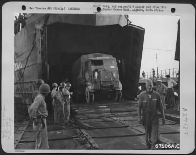 Thumbnail for Consolidated > A truck, loaded with equipment, rolls down the ramp of the LST (Landing Ship Tanks) onto a floating pier. Sicily, July 1943.