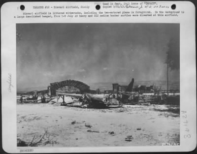 Consolidated > Biscari airfield is littered withwrecks, including the two-motored plane in foreground. In the background is a large demolished hangar, from 5-9 July 49 heavy and 212 medium bomber sorties were directed at this airfield.