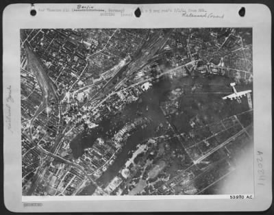Consolidated > One of the attacking Consolidated B-24 Liberators of the U.S. 8th AF roars over the Friedrichsfelde district of central Berlin 21 June 44 as initial bursts erupt on the rail marshalling yards there. Bombardment Group.