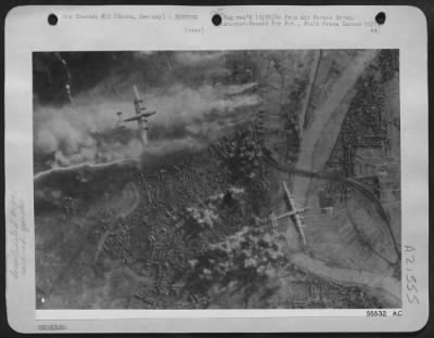 Consolidated > Multi-column smoke surges from the Hanau, German marshalling yards as new bomb bursts mushroom nearby. This photo was taken during the 8th Air Force Consolidated B-24 Liberator daylight attack on communications, 12 Dec 44.
