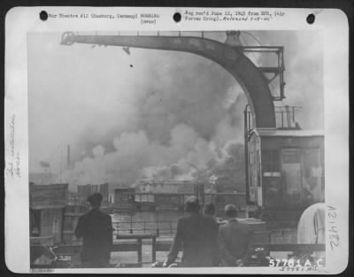 Thumbnail for Consolidated > German Caption Writers Wrote On This Picture -------'...Der Deutschen Werfe In Flammen.  Flames And Smoke Fill The Sky Around The Deutsche Werkes Where Submarines Were Under Construction.  German On-Lookers Stand By, Watching The Spectacle Of Devastation